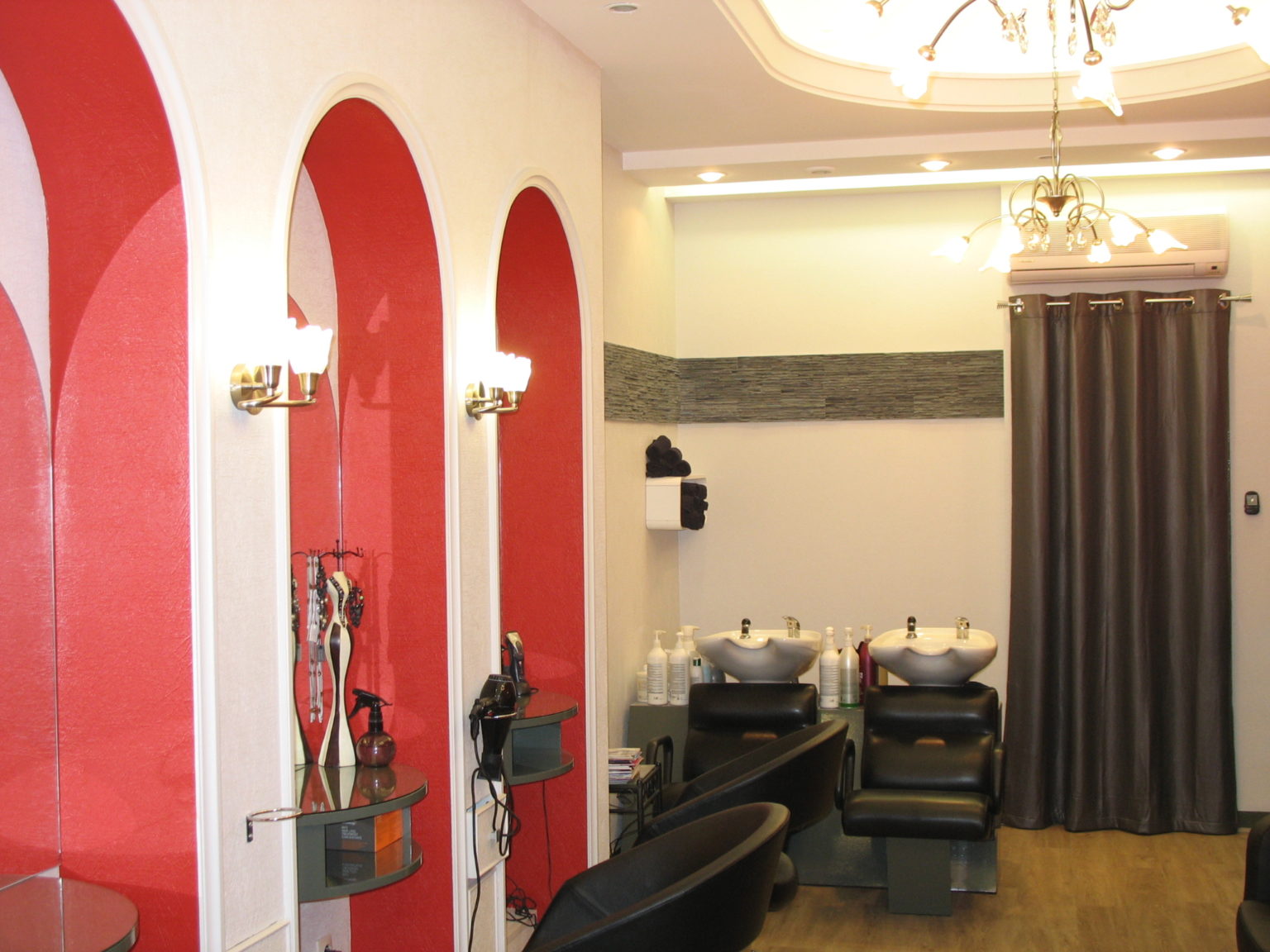 Photographie dans un salon de coiffure où les murs ont été repeints en blanc et des alcoves en rouge