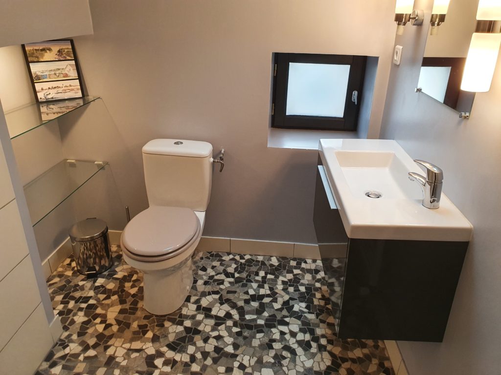 Photographie d'une salle de bain avec le sol en carrelage mosaïque et le mur peint en gris