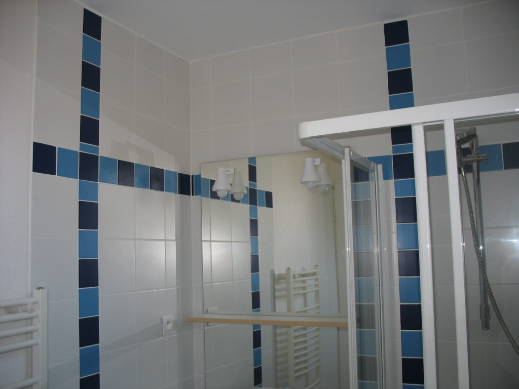 Murs de salle de bain blancs avec quelques carrelages bleu foncé et bleu clair