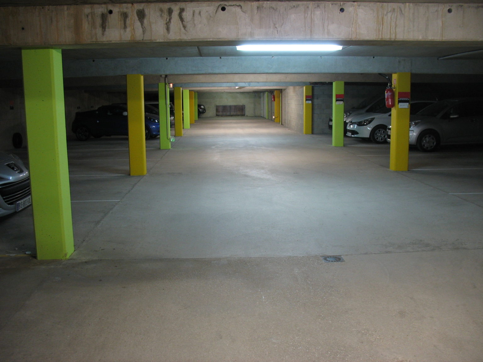 Photographie dans un garage souterrain où les colonnes ont été repeintes en vert pomme et jaune